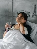 COvid 19 cough // sick woman lying in bed with glass of water in hand // Healthier Me Today