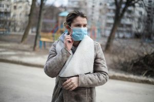 Covid 19 cough // woman standing in street wearing a blue face mask