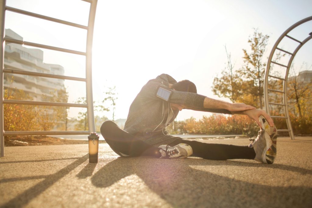 man stretching, winter gym clothes, earphones, outside // Healthier Me Today