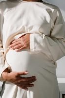 woman holding pregnant belly, wearing a shite cover up, white wall // Healthier Me Today