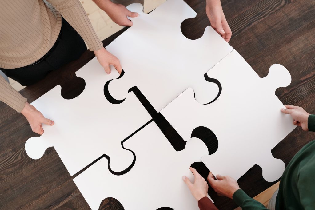 close shot, group putting big puzzle pieces together, white puzzle pieces, wooden floor // Healthier Me Today 