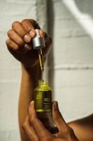 carrier oil, woman holding bottle of oil, bottle in one hand and the lid in the other, white wall // Healthier Me Today