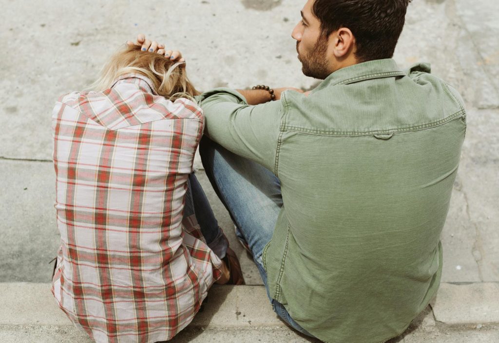 man and women sitting on a step, concrete floor, having relationship problems // Healthier Me Today