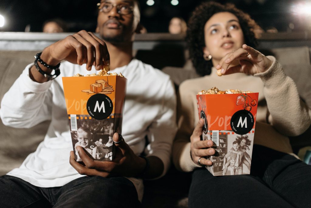 couple watching movie, eating popcorn, couple sitting on seats, man is wearing glasses // Healthier Me Today