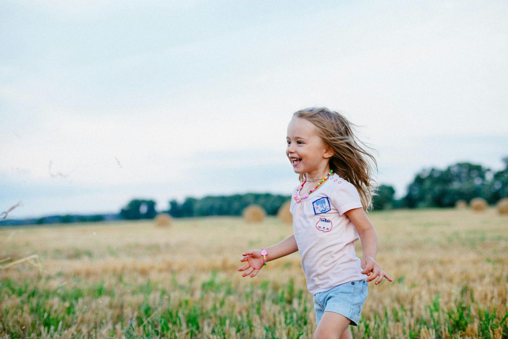 little girl running, happy girl, field of grass, cloudy, trees in the distance // Healthier Me Today