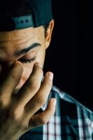 close shot of man, eyes closed, holding his head, black hat, checked shirt, black // Healthier Me Today