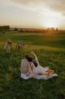 couple having a picnic, watching the sunset, two bicycles, open field of grass // Healthier Me Today