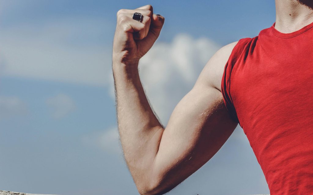 man flexing, bicep, red vest, cloudy // Healthier Me Today