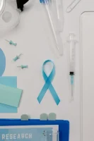 A Blue Ribbon Symbol for Prostate Cancer Beside a Syringe on White Surface // Healthier Me Today