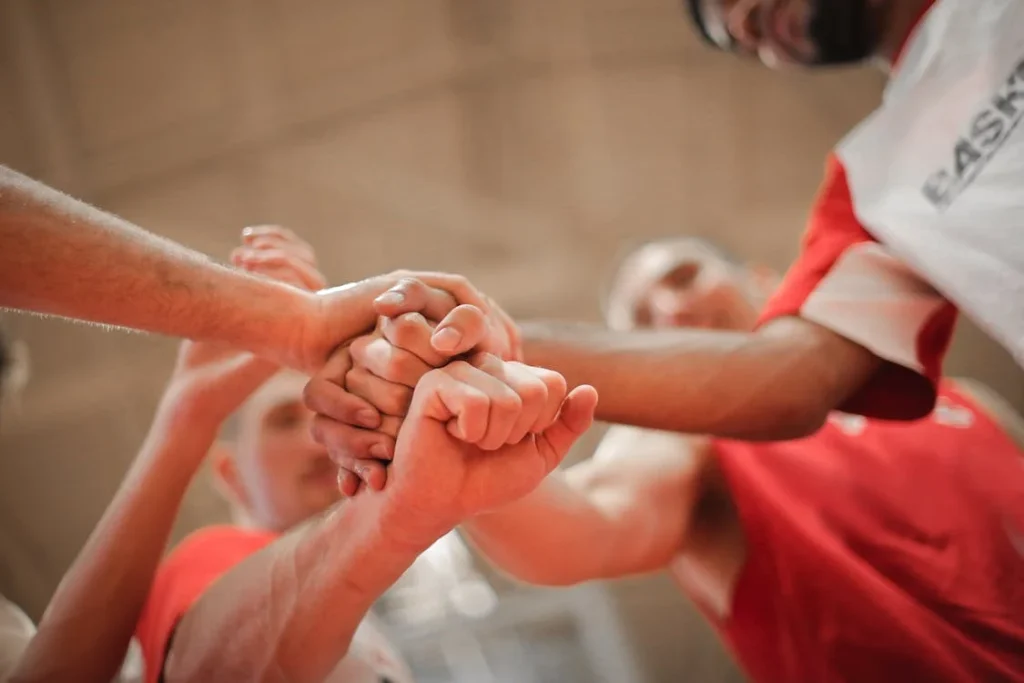 Basketball team stacking hands together // Healthier Me Today