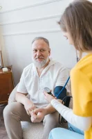 Woman Measuring the Blood Pressure of an Elderly Man with a Blood Pressure Monitor // Healthier Me Today